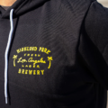 close up on logo on black highland park brewery pullover with fresh los angeles lager artwork