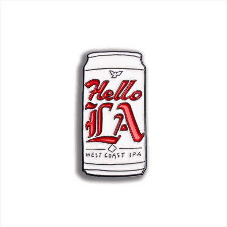 The Hello LA Enamel Pin (2025) is beer can-shaped, featuring "Hello LA" in bold red script and "West Coast IPA" in small black text on a white background.