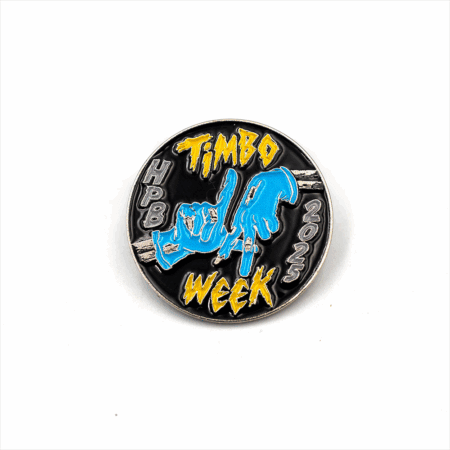 The Timbo Week Pin (2025) features "Timbo Week 2025" in yellow, blue hands making hand signs in the center, and "HPB" on the left side, all set against a black background.
