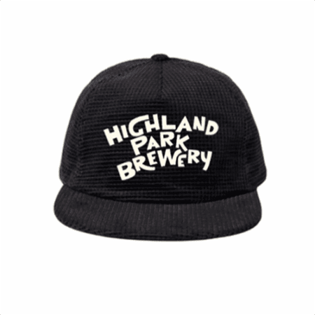 The Highland Park Brewery Corduroy Hat is a black cap featuring bold, white, playful "Highland Park Brewery" lettering on the front, shown on a plain white background.