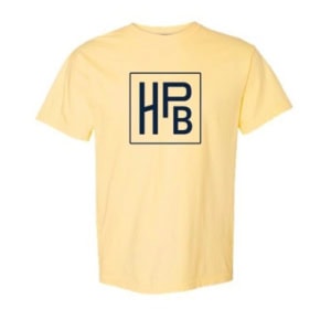 The HPB Logo Tee - Yellow is a light yellow t-shirt with a bold navy blue "HPB" monogram inside a square on the center chest.