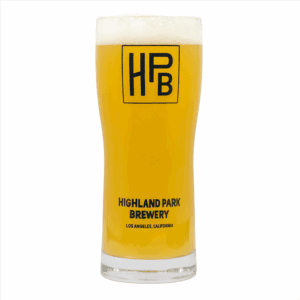 A tall glass of hazy, golden beer with a foamy head, served in the Classic Logo Glassware labeled "HPB" and "Highland Park Brewery, Los Angeles, California.