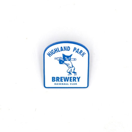 The Sad Cat Baseball League Pin (2026) is a white and blue pin showing a cartoon cat with a baseball bat, plus "Highland Park Brewery Baseball Club" in bold blue letters above and below the cat.