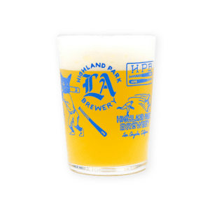 A hazy yellow beer with a foamy head served in the HPB Baseball Maxi Tumbler, which features blue graphics and text reading "Highland Park Brewery" and "Los Angeles, California" on its side.