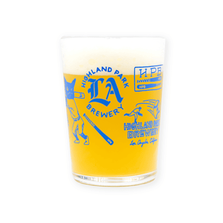 A hazy yellow beer with a foamy head served in the HPB Baseball Maxi Tumbler, which features blue graphics and text reading "Highland Park Brewery" and "Los Angeles, California" on its side.