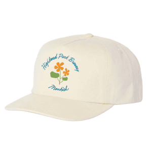 A cream-colored baseball cap featuring the text "Highland Park Brewery" and "Monkish" above and below an illustration of three orange flowers with green leaves.