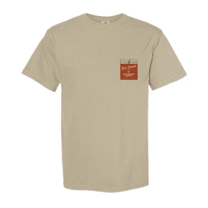 The Lone Pine x HPB Tee is a beige short-sleeve shirt featuring a small red and white name tag-style graphic with text on the left chest.